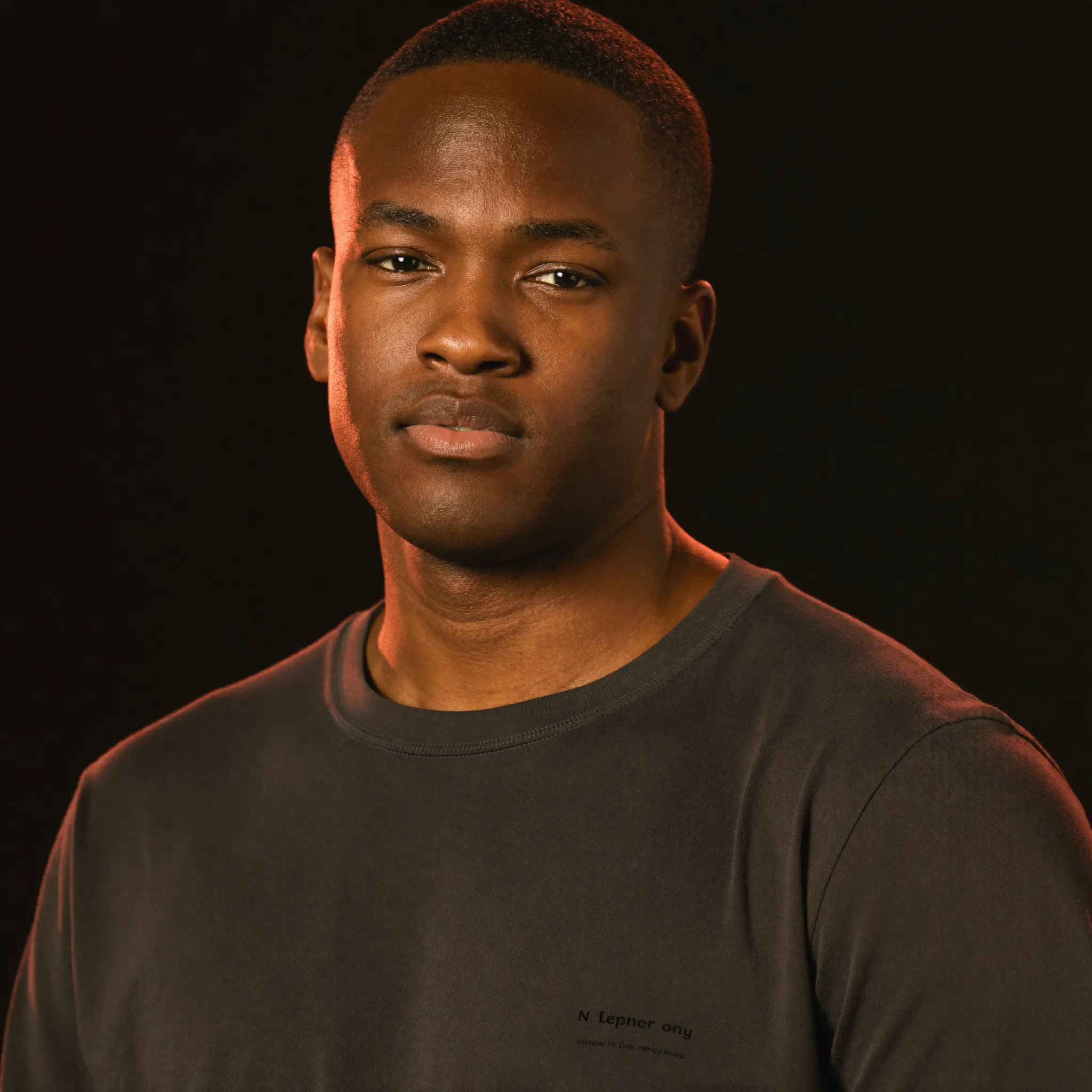 Portrait of Marcus, a Black indie SaaS founder who builds in public, wearing a charcoal FantoClient t-shirt with warm rim light