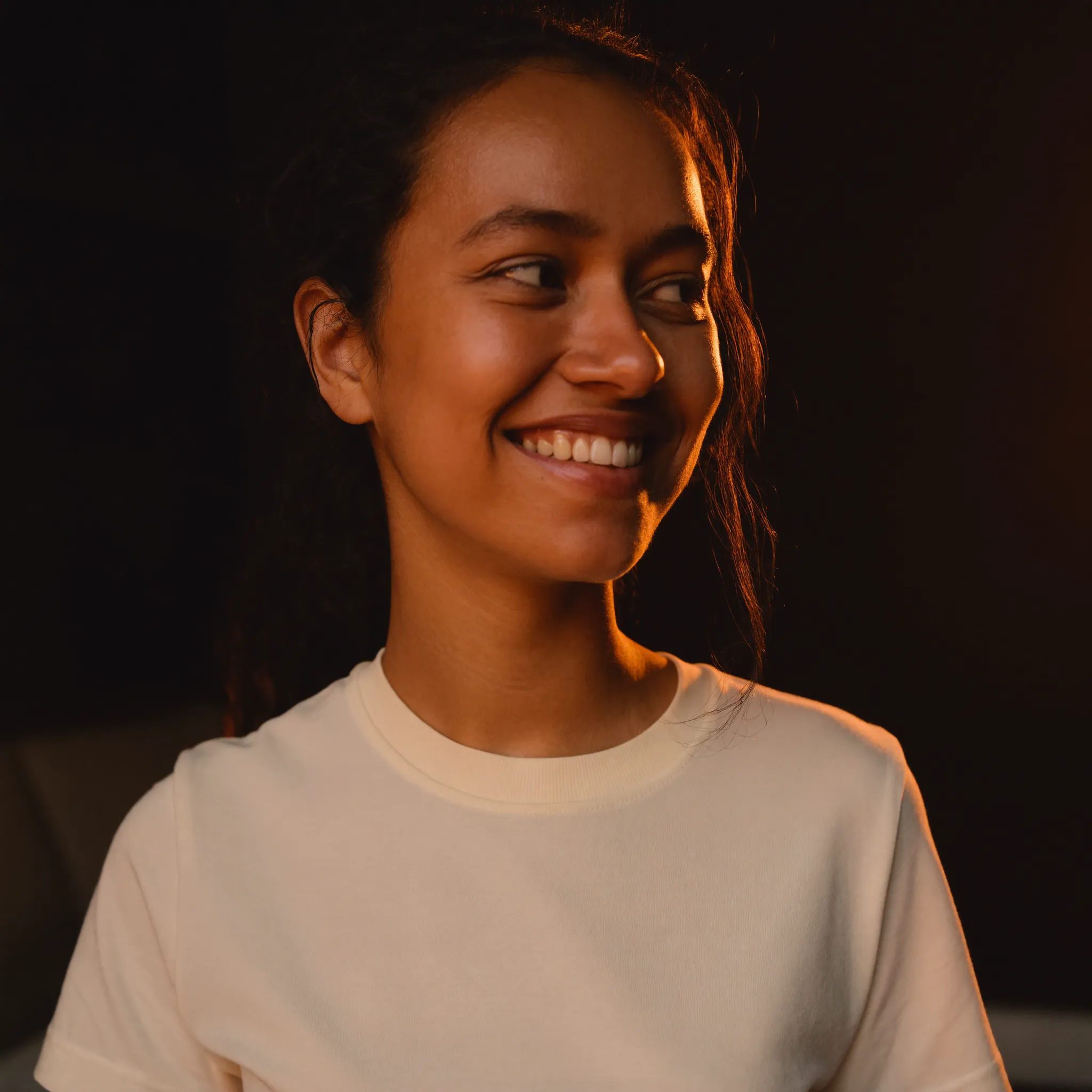 Portrait of Sofia, a Latina freelance copywriter who sells project-based work, wearing a cream FantoClient t-shirt with warm key light